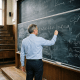 Professor writing advanced mathematical equations on a chalkboard in lecture hall