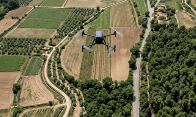 Drone flying above patchwork farmland near a village